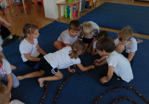 Dzieci na dywanie układają ścieżkę z kasztanów